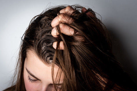 A woman running her fingers through clean, glossy hair in soft natural daylight